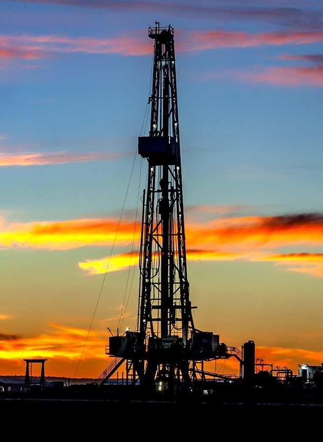 Oil drilling rig against a sunset sky